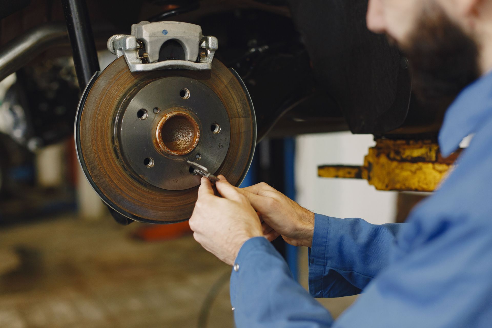 Mechanic working on brake disc in an auto repair workshop, close-up, focus on hands.